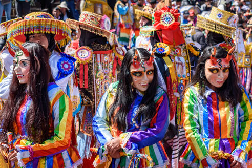 Cusco, a cultural fiesta, people dressed in traditional colourful costumes with masks and hats, brightly coloured streamers. - MINF16681