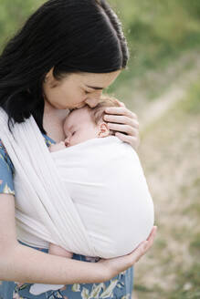 Mutter küsst Tochter in Babytrage gewickelt - SSYF00162