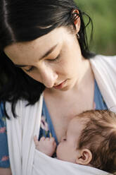 Mutter betrachtet ihre Tochter, die in Babykleidung ruht - SSYF00167