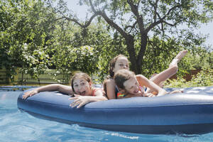 Friends having fun lying on pool raft in swimming pool - OSF01894