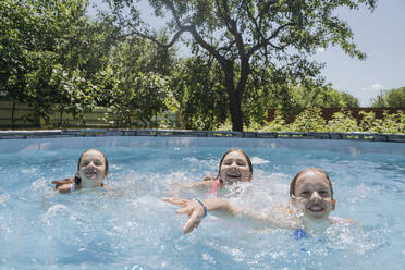 Lächelnde Freunde, die im Sommer im Pool planschen - OSF01897