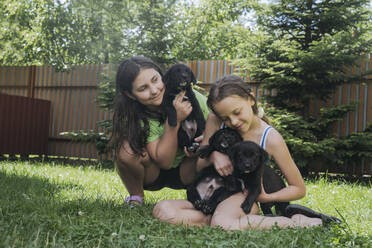 Smiling friends playing with dogs in back yard - OSF01901