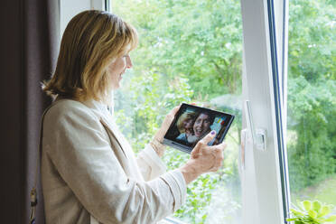 Reife Frau im Videogespräch mit Tochter und Enkelin über Tablet-PC - IHF01566