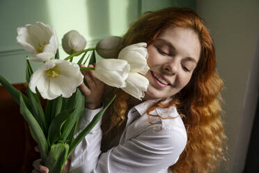 Schöne Frau hält einen Strauß Tulpenblüten zu Hause - YBF00001