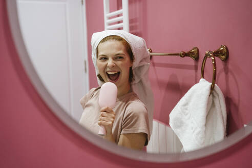 Frau hält Haarbürste und singt im Badezimmer - YBF00021