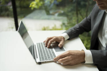 Hände eines Geschäftsmannes beim Tippen auf einem Laptop im Büro - SVKF01511