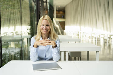 Confident businesswoman with laptop at desk in office - SVKF01513