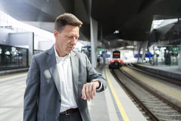 Reifer Geschäftsmann, der die Zeit am Bahnhof kontrolliert - SVKF01544