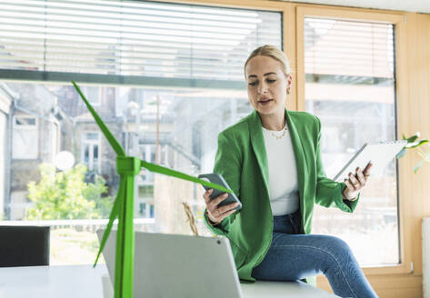 Geschäftsfrau hält Tablet-PC und benutzt Smartphone im Büro - UUF29588