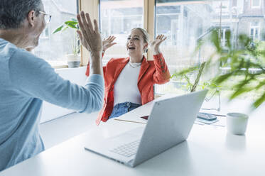 Cheerful businessman and businesswoman giving high-five to each other - UUF29605