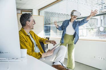 Happy businessman with colleague wearing virtual reality simulators - UUF29636