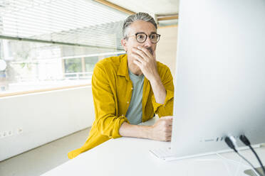 Besorgter Geschäftsmann arbeitet am Desktop-PC im Büro - UUF29643