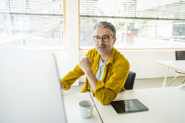 Businessman wearing eyeglasses working on desktop PC in office - UUF29648