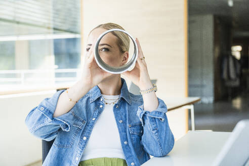 Businesswoman looking through metallic circular equipment - UUF29654