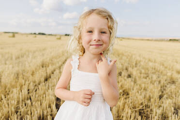 Smiling blond girl standing in stubble field - SIF00703
