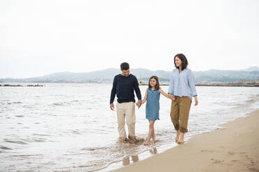 Glückliche Familie, die sich an den Händen hält und gemeinsam am Strand spazieren geht - JOSEF19980