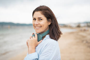 Happy woman with wireless headphones at beach - JOSEF19982