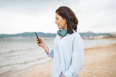 Lächelnde Frau mit Smartphone am Strand - JOSEF19984