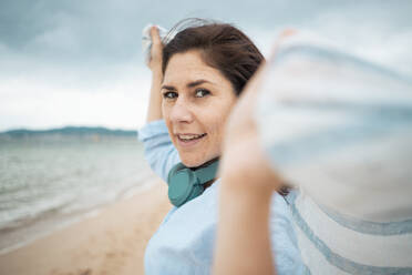 Happy woman with scarf enjoying at beach - JOSEF19988