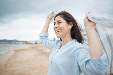 Cheerful woman with scarf enjoying at beach - JOSEF19990