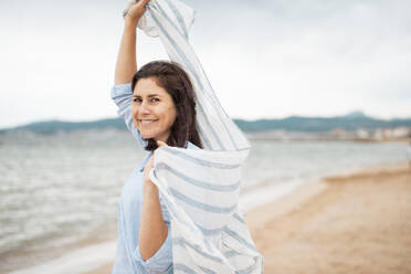 Smiling woman with scarf having fun at beach - JOSEF20004