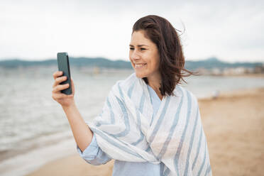 Smiling woman taking selfie through smart phone at beach - JOSEF20007