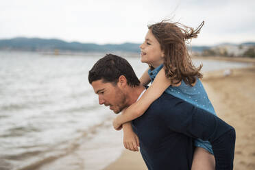 Father giving piggyback ride to daughter at beach - JOSEF20012