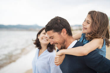 Happy girl with father giving piggyback ride and having fun at beach - JOSEF20017