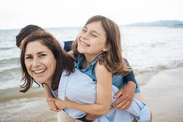 Happy mother and daughter enjoying with father at beach - JOSEF20036