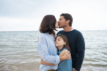 Vater und Mutter küssen sich mit Tochter vor dem Meer - JOSEF20050