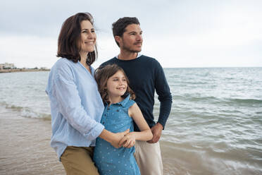 Happy woman standing with family at beach - JOSEF20052