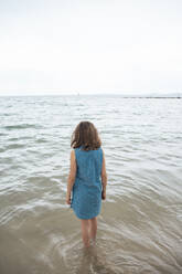 Mädchen steht im Wasser am Strand unter Himmel - JOSEF20056