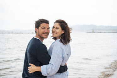 Glücklicher Mann und Frau stehen zusammen vor dem Meer am Strand - JOSEF20060