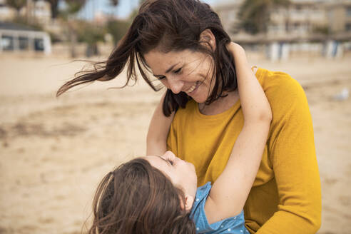 Cheerful woman enjoying with daughter at beach - JOSEF20110