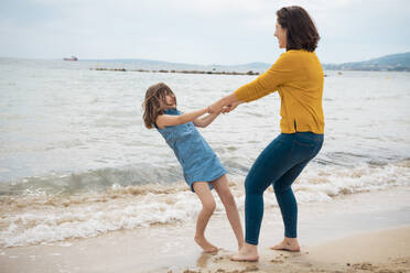 Glückliche Mutter hält Hände mit Tochter und spielen vor dem Meer - JOSEF20119