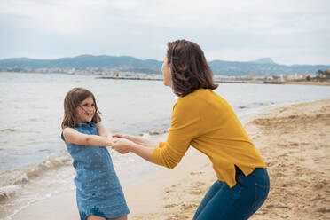 Glückliches Mädchen hält Hände und hat Spaß mit Mutter am Strand - JOSEF20124