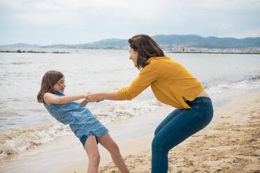 Glückliche Tochter, die mit ihrer Mutter Händchen hält und Spaß am Strand hat - JOSEF20126