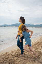 Happy mother and daughter playing and having fun at beach - JOSEF20129