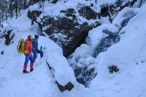 Paar in Skikleidung beim Wandern auf einem schneebedeckten Berg - ANSF00434