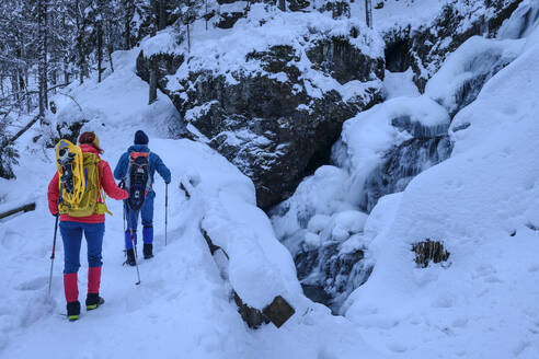 Paar in Skikleidung beim Wandern auf einem schneebedeckten Berg - ANSF00435