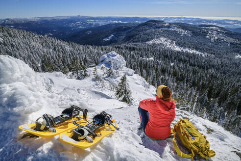 Woman resting with ski and backpack on snow covered mountain - ANSF00442