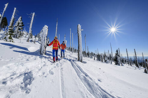 Couple skiing on snow covered landscape on sunny day - ANSF00460