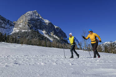 Couple skiing on snowcapped landscape by rocky mountain - ANSF00463