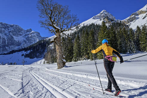 Woman skiing on snowy landscape towards Karwendel Mountains - ANSF00465