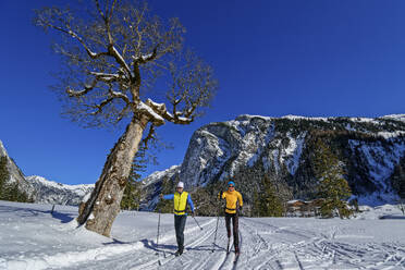 Pärchen beim Skifahren in verschneiter Landschaft vor dem Karwendelgebirge - ANSF00468