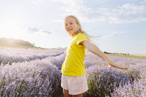 Happy girl with arms outstretched standing in lavender field under sky - SIF00717