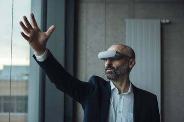 Mature businessman gesturing with virtual reality simulators - JOSEF20145