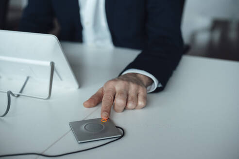 Die Hand eines Geschäftsmannes drückt einen Knopf am Schreibtisch - JOSEF20191