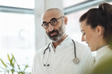 Mature doctor with smiling colleague in hospital - JOSEF20213