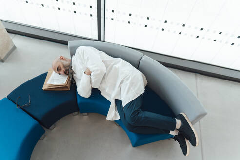 Tired doctor resting on sofa in hospital - JOSEF20218